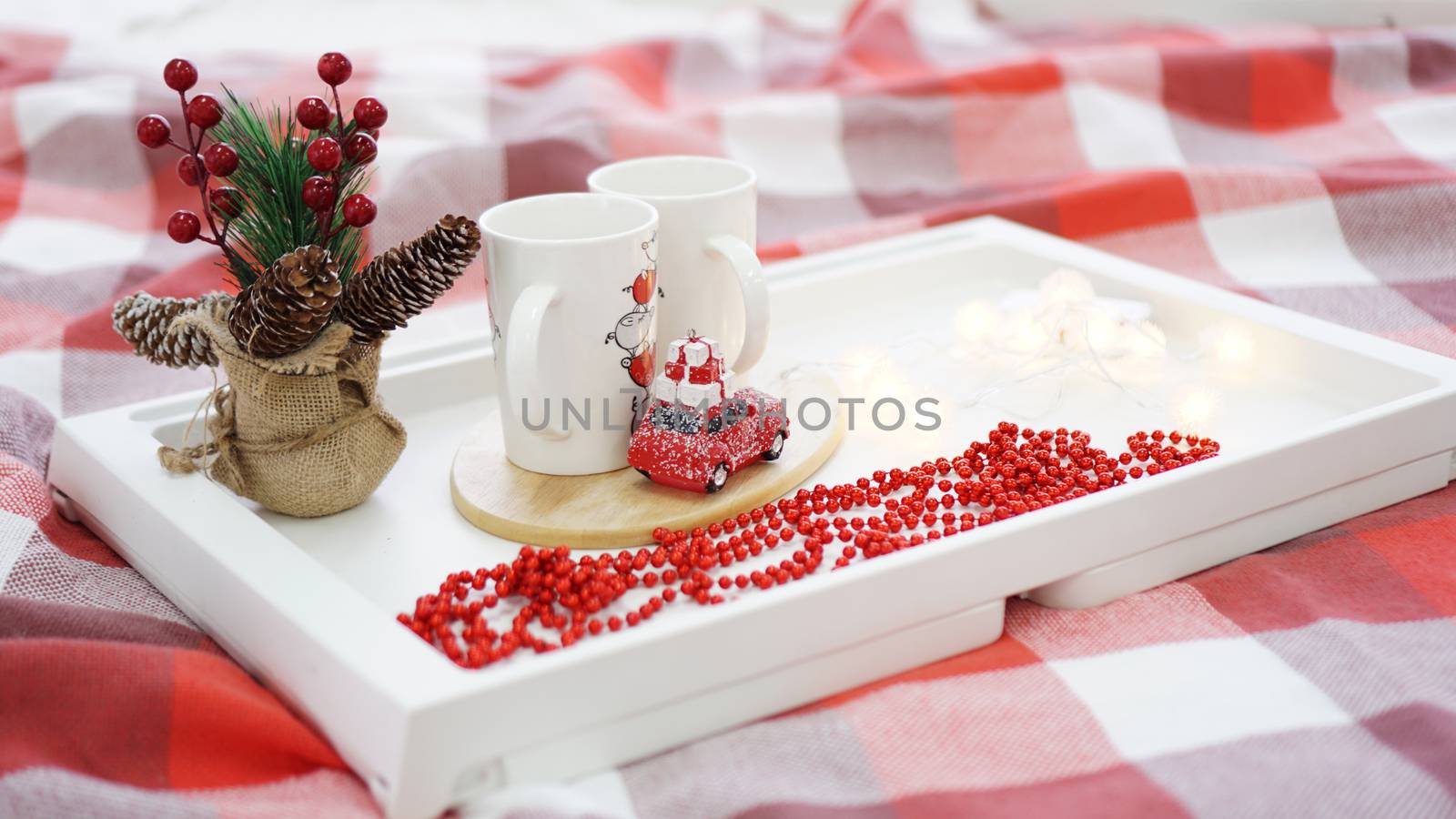 New Year or Christmas red mug on white tray in red and white bed with lights