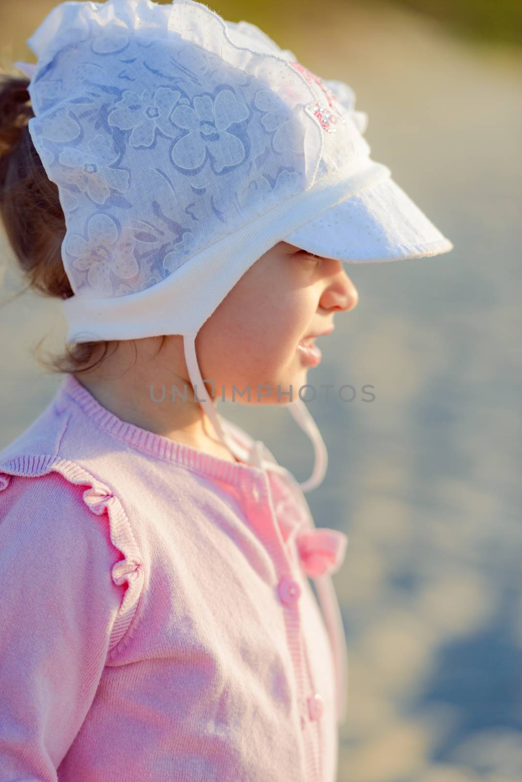 Adorable toddler girl on a sunny sand beach. Authentic childhood