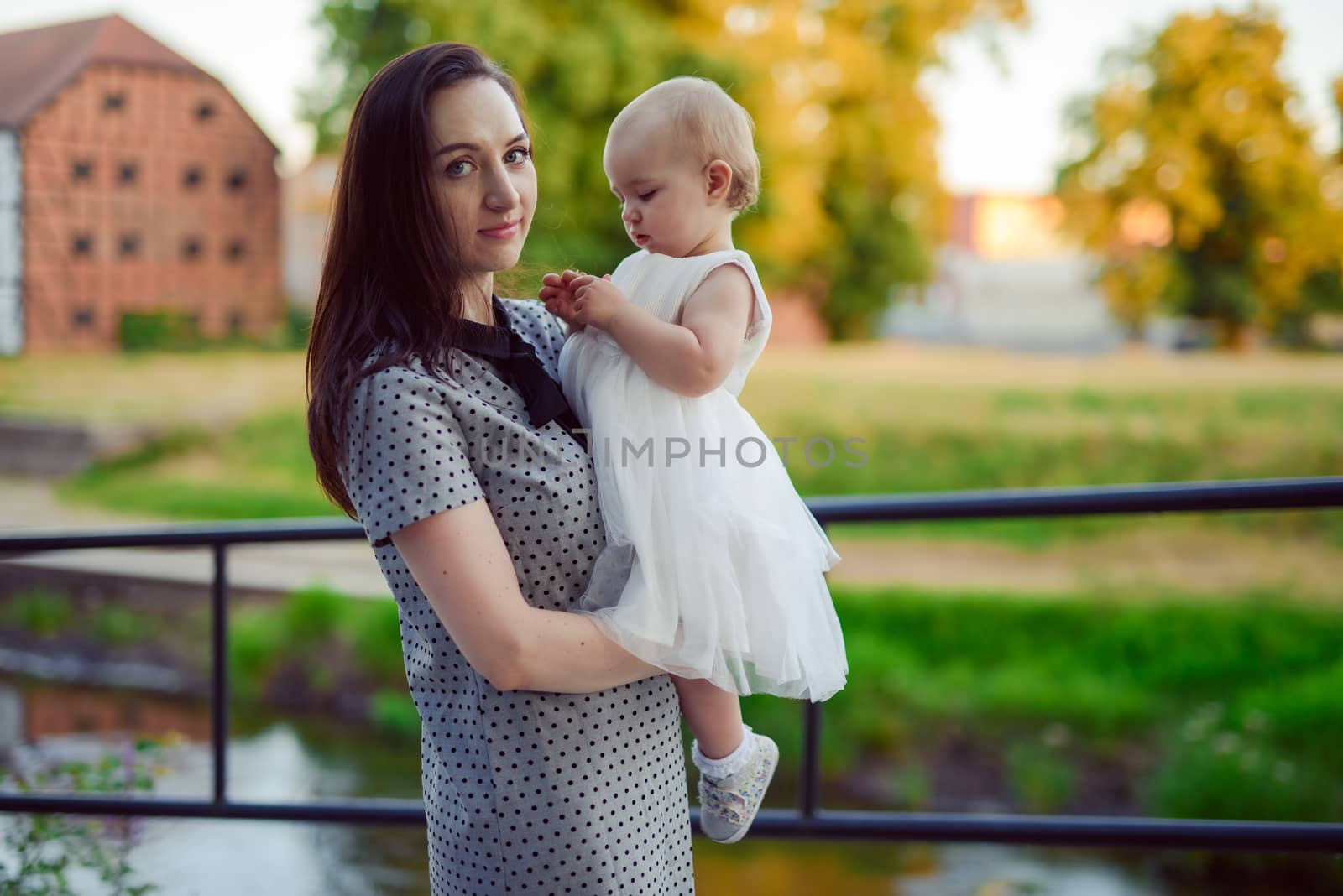 Happy mother and daughter in the park. Beauty nature scene with family outdoor lifestyle. Happy family resting together on the green grass, having fun outdoor. Happiness and harmony in family life.