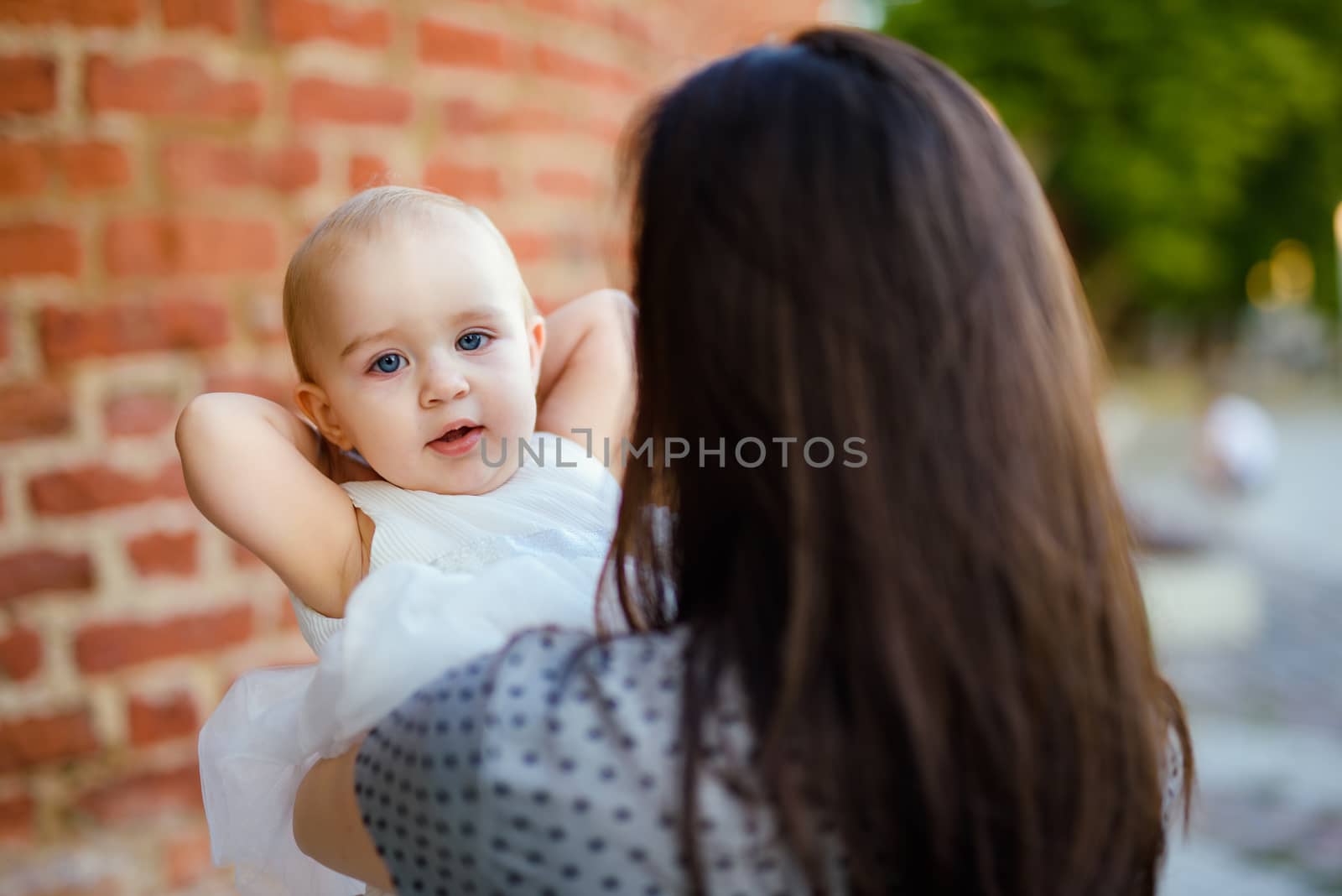 Happy mother and daughter in the park. Beauty nature scene with family outdoor lifestyle. Happy family resting together on the green grass, having fun outdoor. Happiness and harmony in family life.