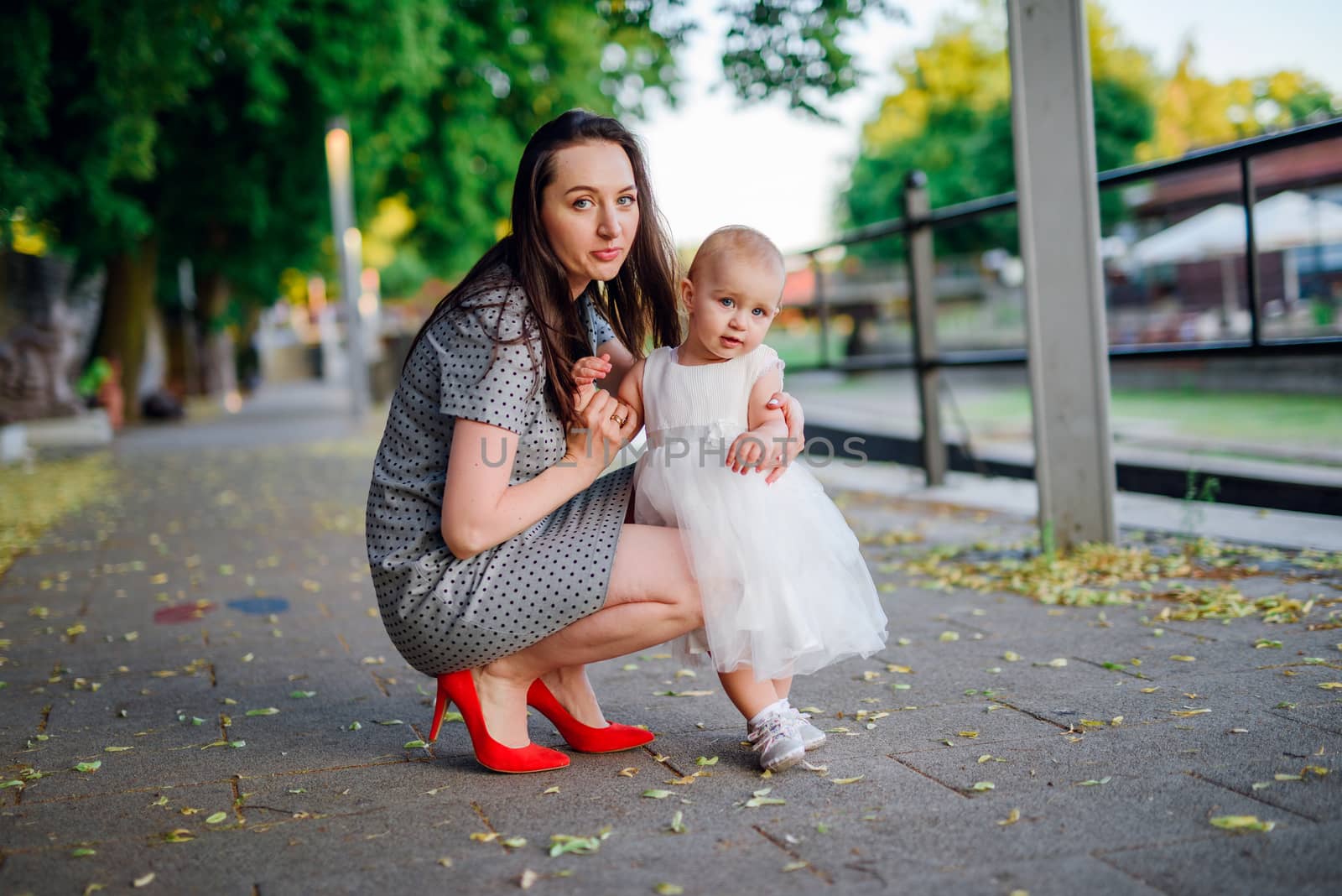 Happy mother and daughter in the park. Beauty nature scene with family outdoor lifestyle. Happy family resting together on the green grass, having fun outdoor. Happiness and harmony in family life.