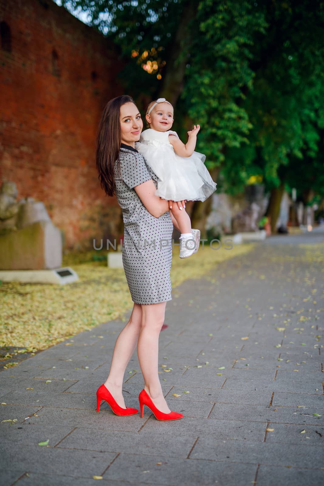 Happy mother and daughter in the park. Beauty nature scene with family outdoor lifestyle. Happy family resting together on the green grass, having fun outdoor. Happiness and harmony in family life.