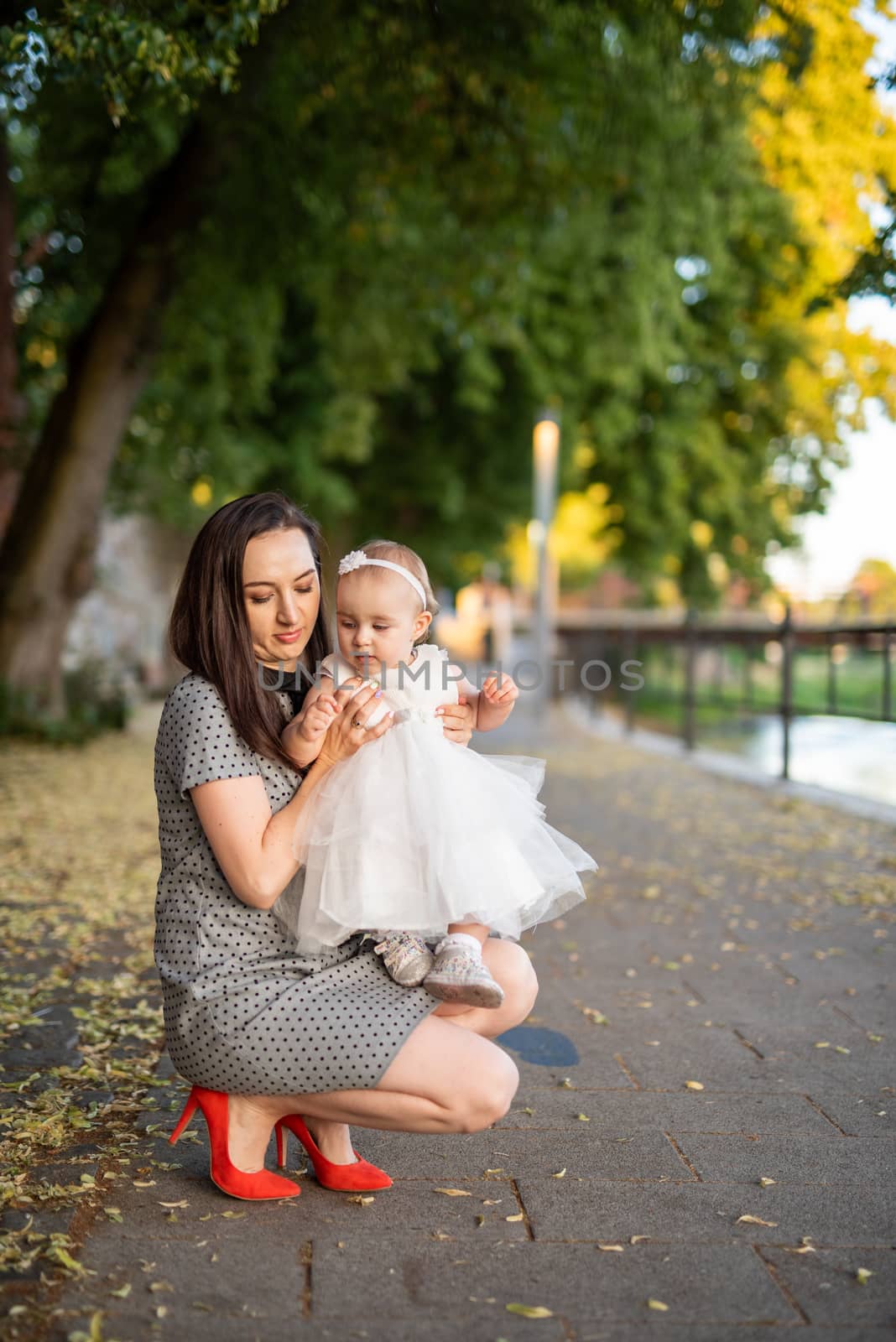 Happy mother and daughter in the park. Beauty nature scene with family outdoor lifestyle. Happy family resting together on the green grass, having fun outdoor. Happiness and harmony in family life.