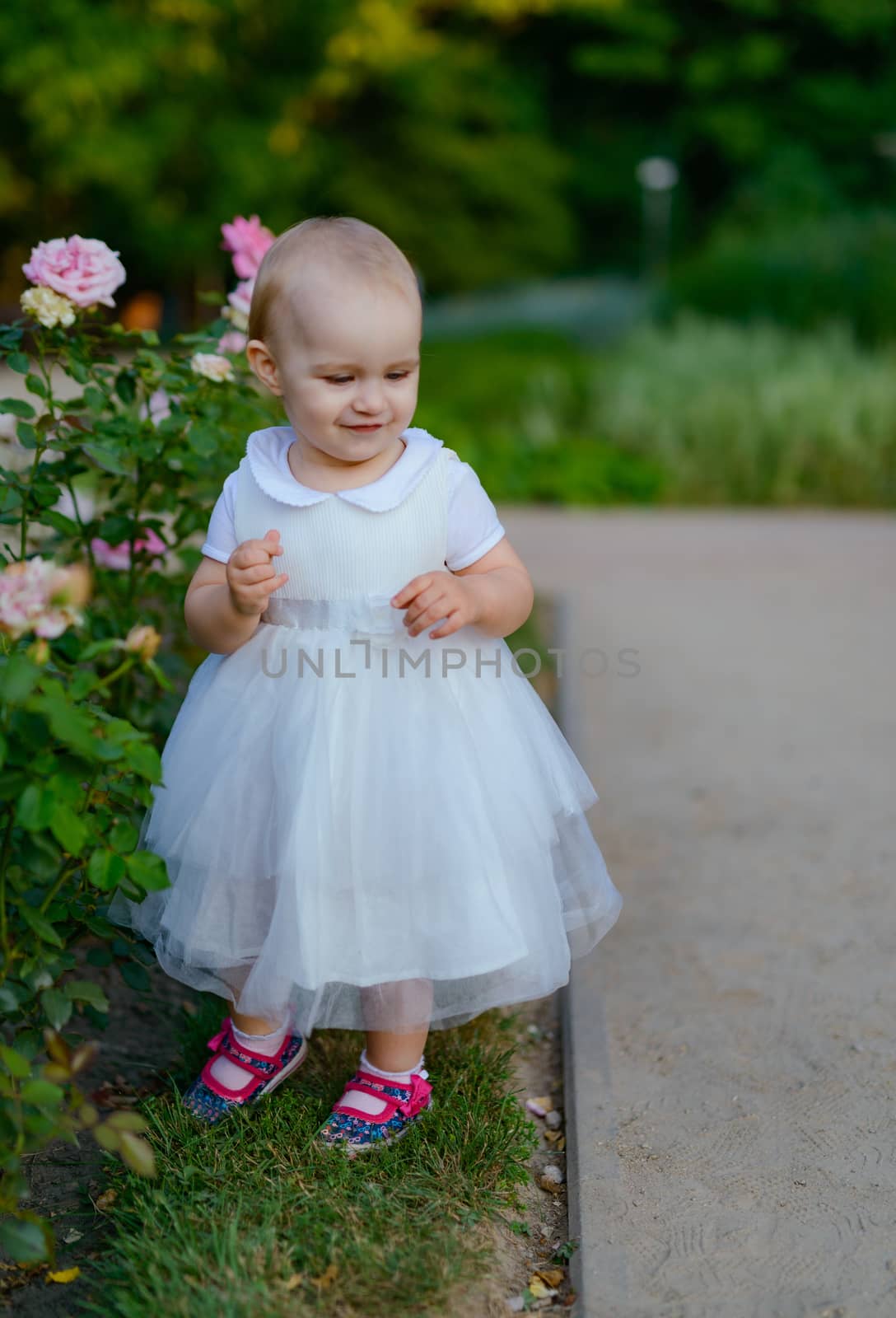 Smiling girl on the meadow looking right at camera. authentic image. Smell roses flowers