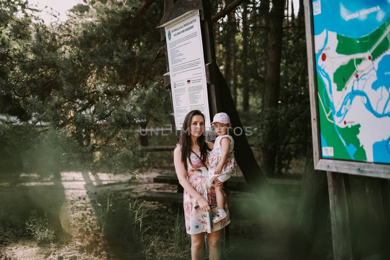 Happy mother and daughter in the park. Beauty nature scene with family outdoor lifestyle. Happy family resting together on the green grass, having fun outdoor. Happiness and harmony in family life.