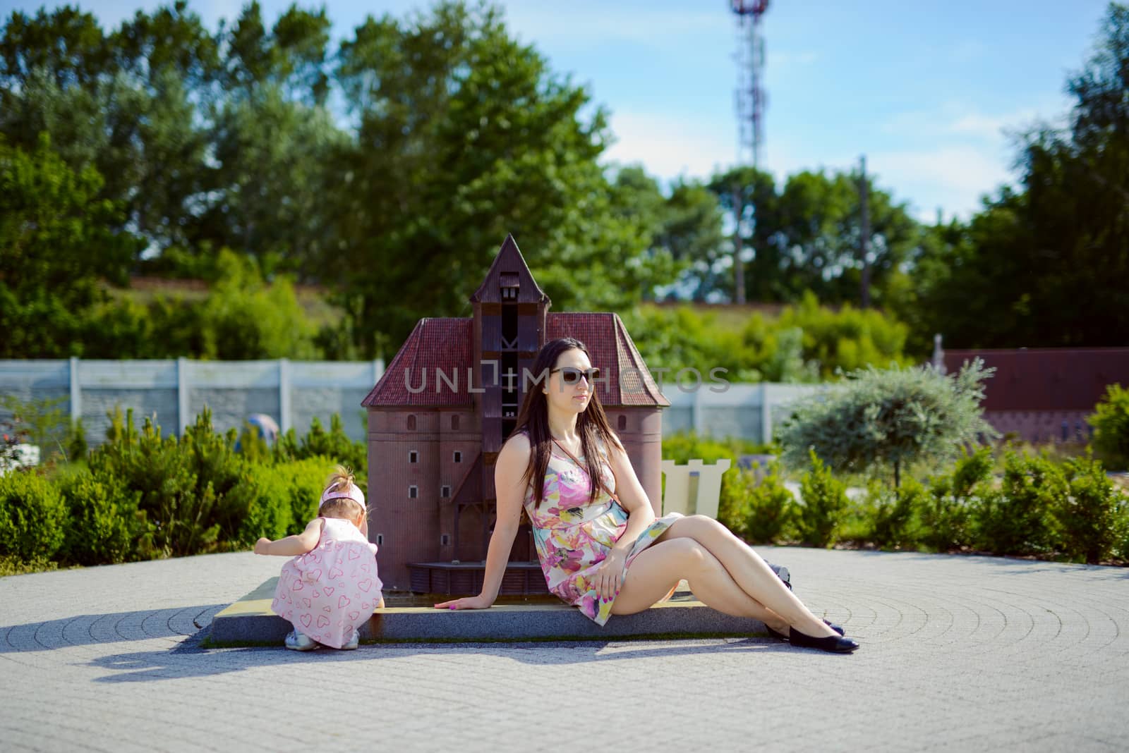 Happy mother and daughter in the park. Beauty nature scene with family outdoor lifestyle. Happy family resting together on the green grass, having fun outdoor. Happiness and harmony in family life.