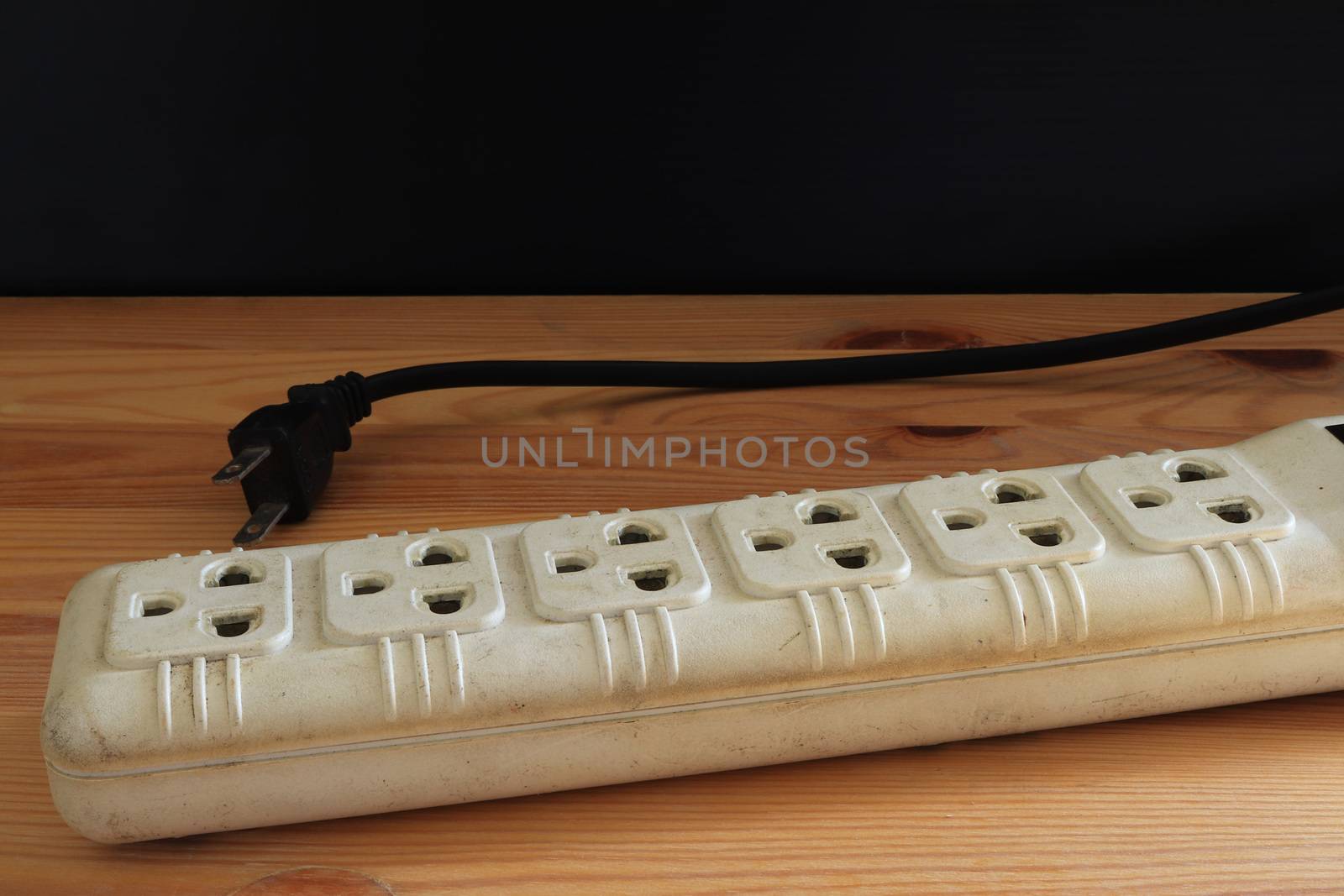 Electric Three eye plug on wooden background and black wall