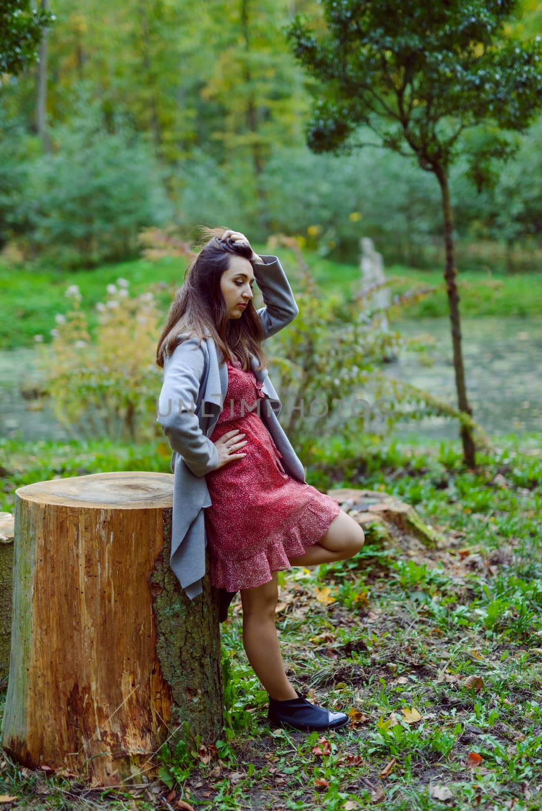 Woman standing next to a tree in park in golden autumn.