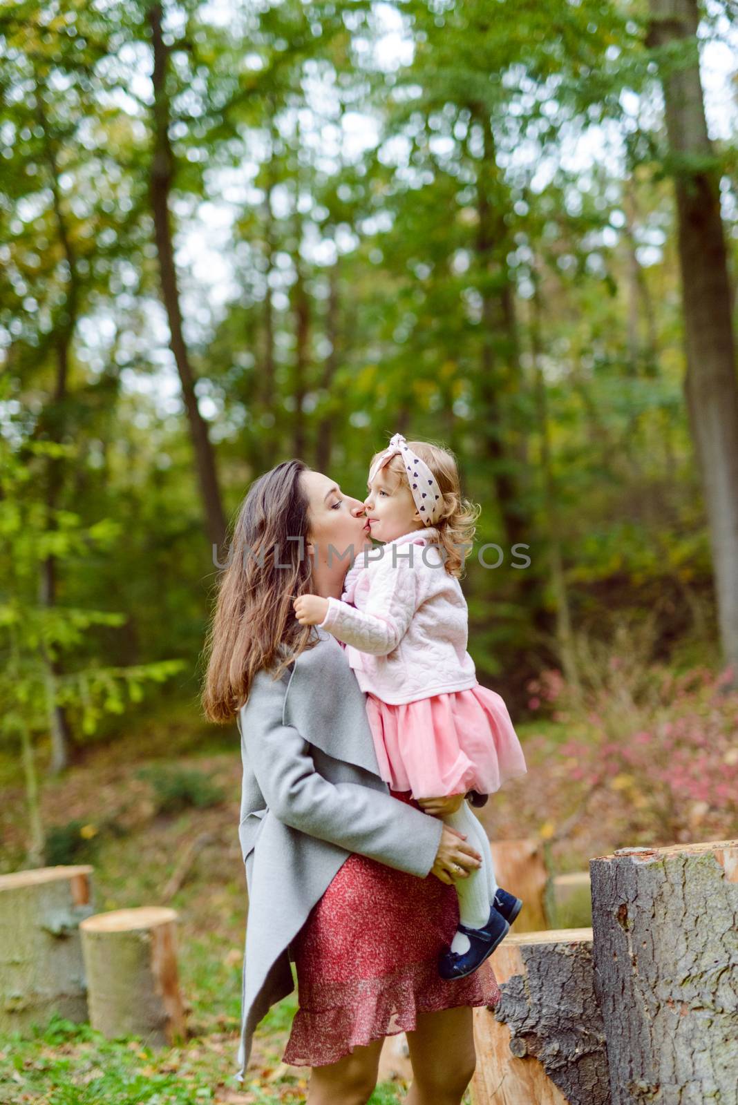 Mother holds daughter in her arms in the park on a sunny day. Autumn day
