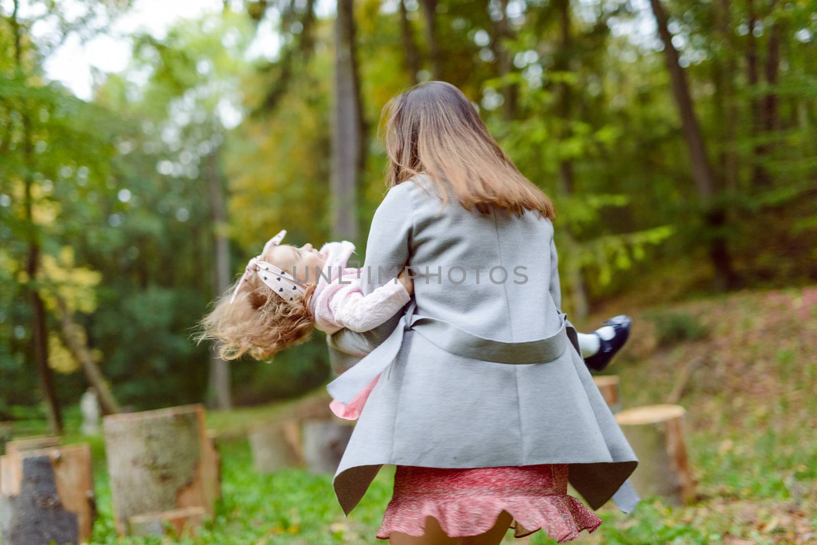Mother holds daughter in her arms in the park on a sunny day. Autumn day