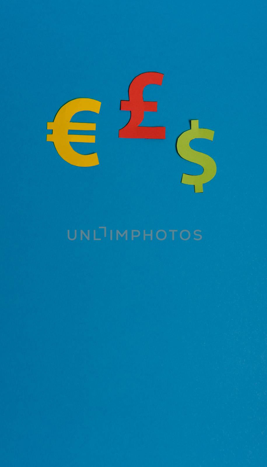 Paper yellow symbols of euro, dollar and pound currency on blue background. View from above with copy space