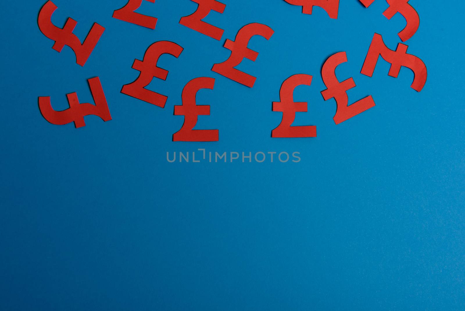 Paper yellow symbols of british pound currency on blue background. View from above with copy space