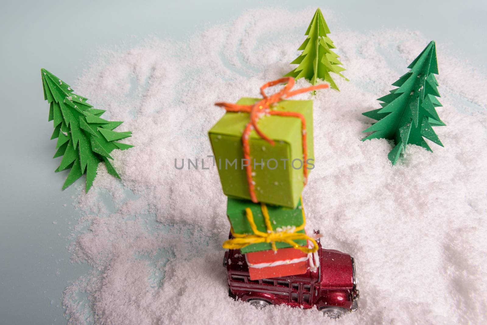 a toy car carries presents under the Christmas tree at snow. view from above. copy space