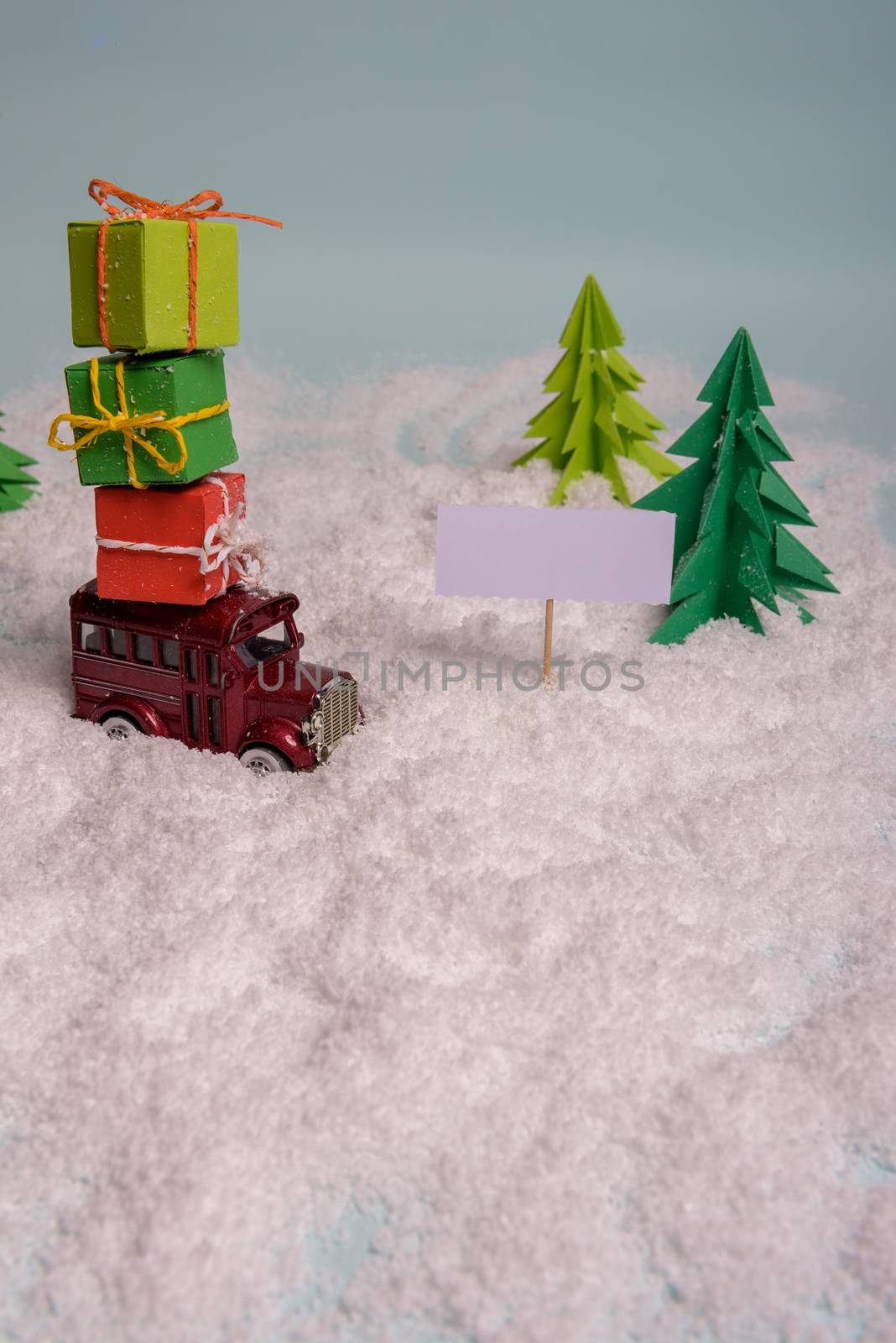 a toy car carries presents under the Christmas tree at snow. view from above. copy space