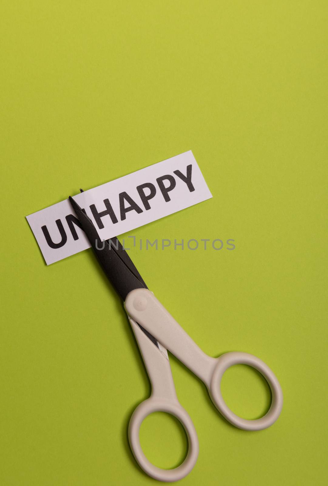 card with text unhappy, cutting word 'un' so it written 'happy'. Copy space. Lime background. Studio shoot.