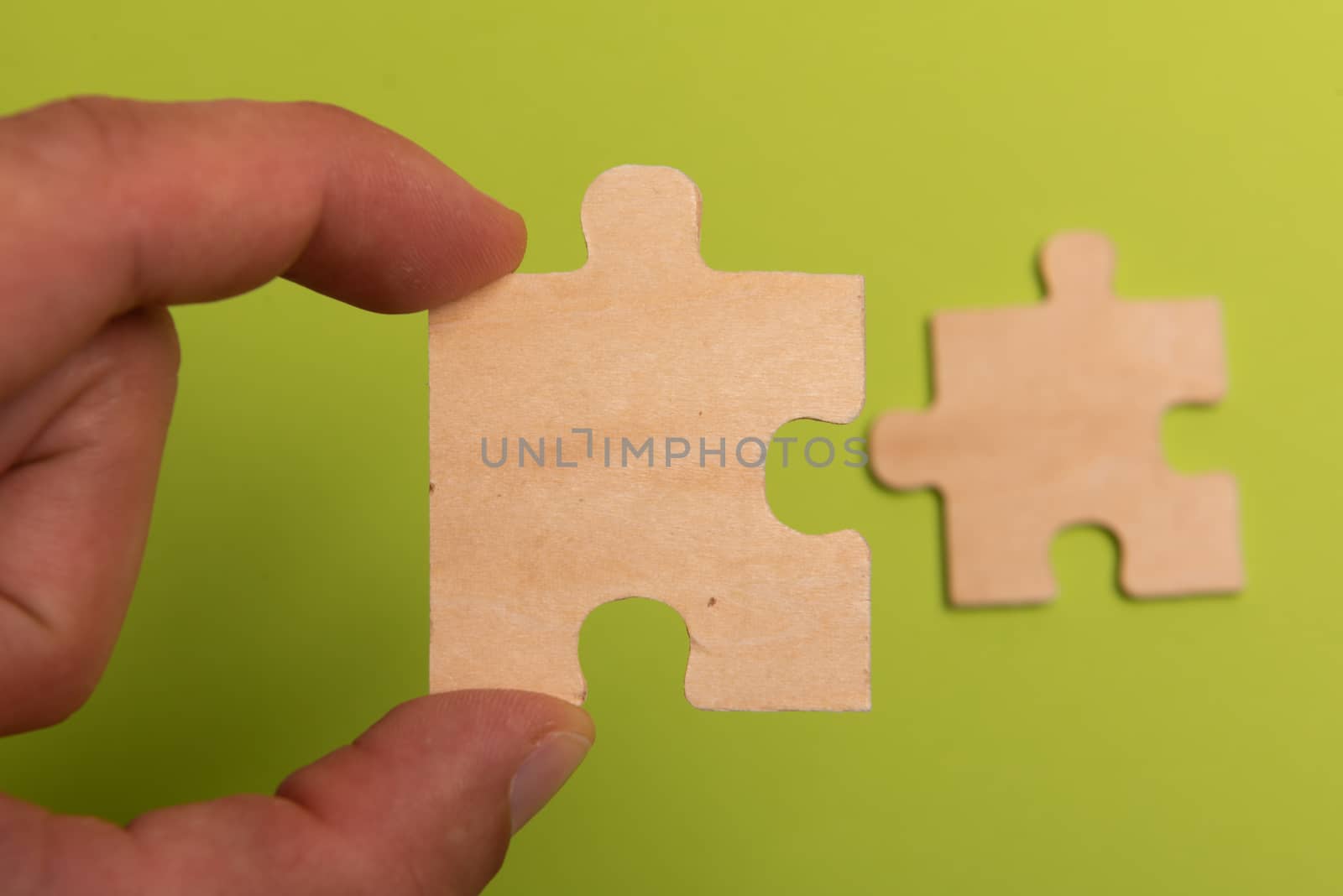 Man hand assembling puzzles on lime background.