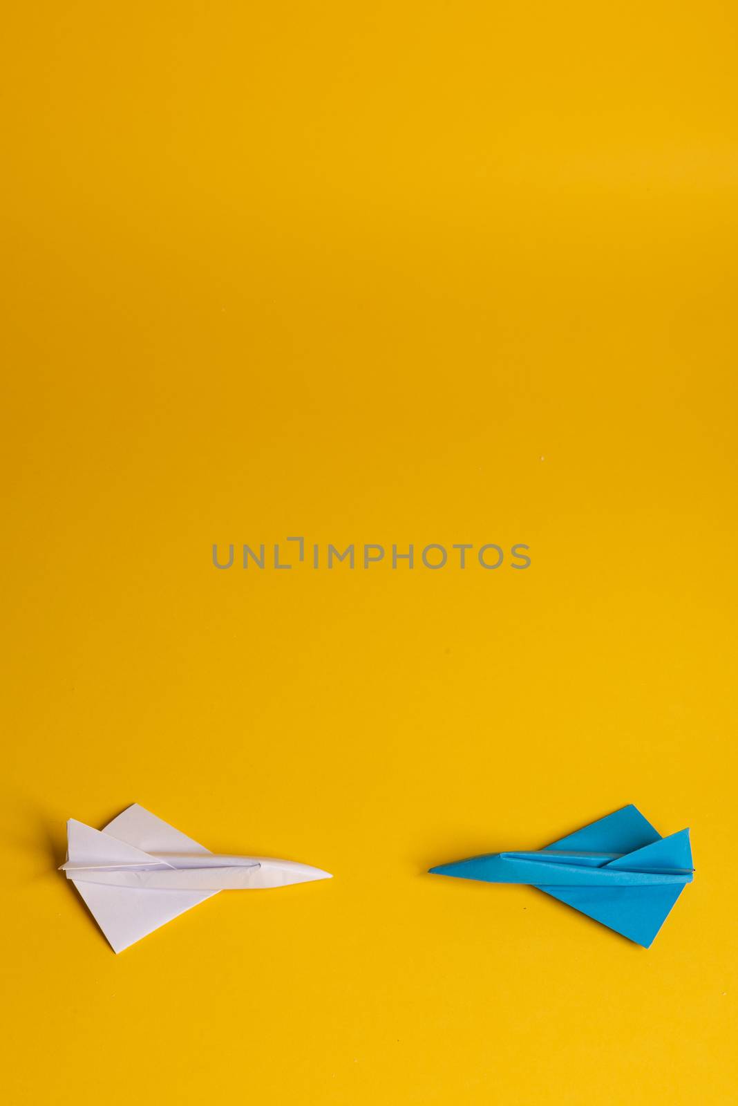 Group of paper plane in one direction and with one individual pointing in the different way on yellow background. Smoke coming out from aircraft tails