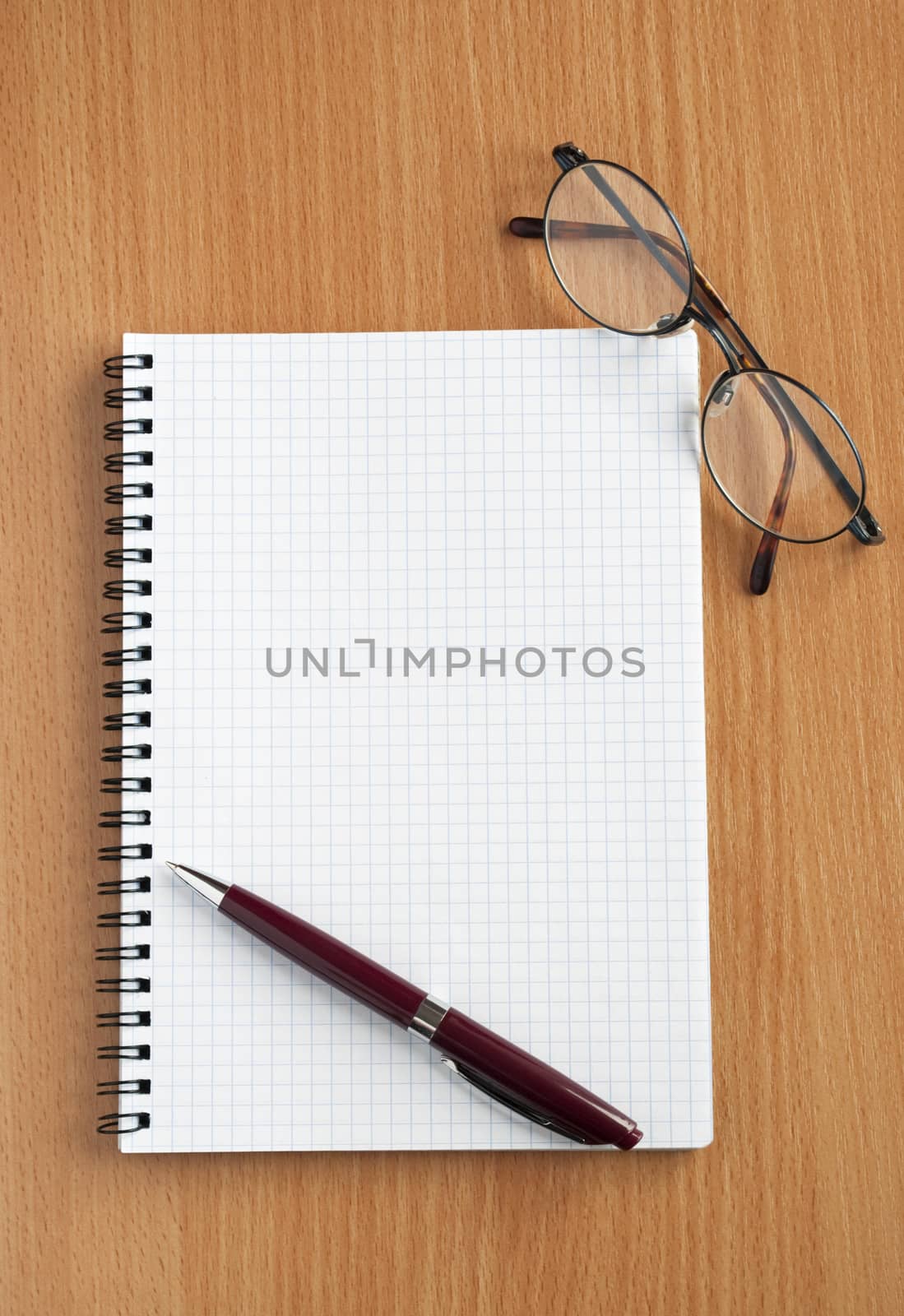 Notebook, glasses and pen on the table.