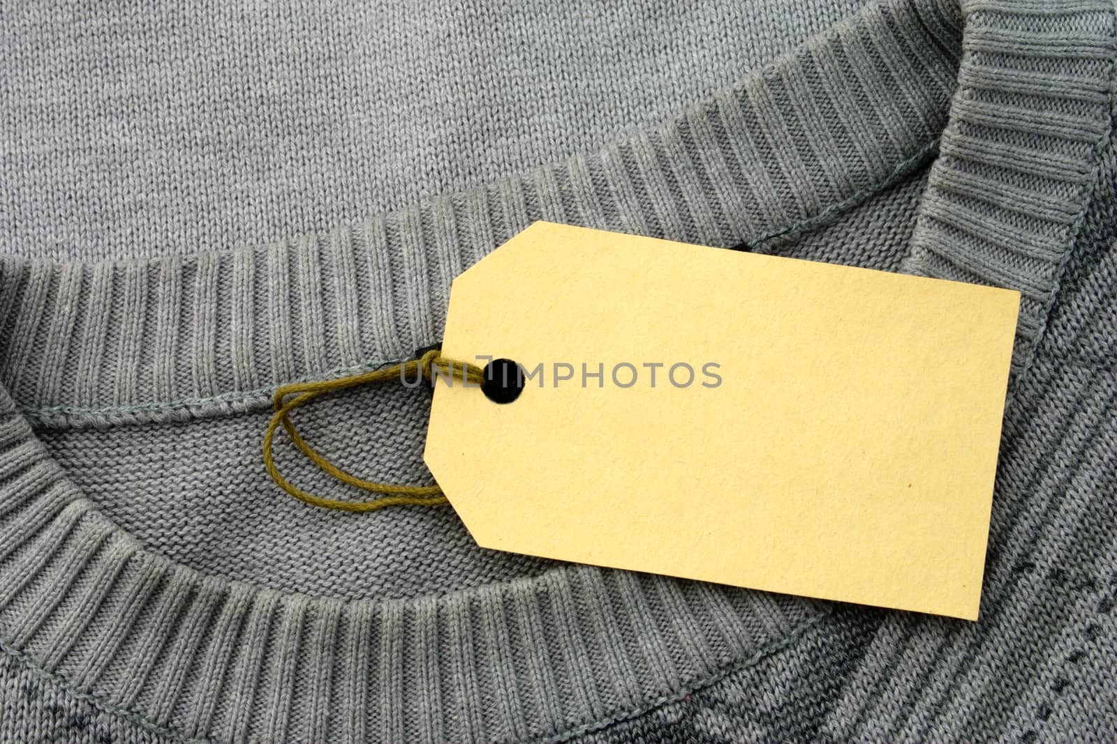 The label is attached to a sweater of gray color