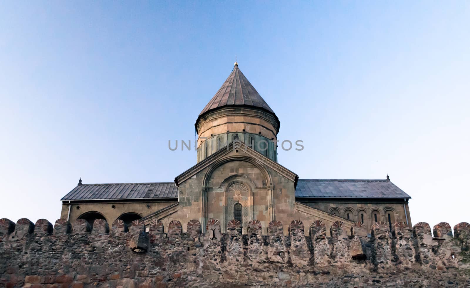 old church with a stone wall in Georgia against a blue sky