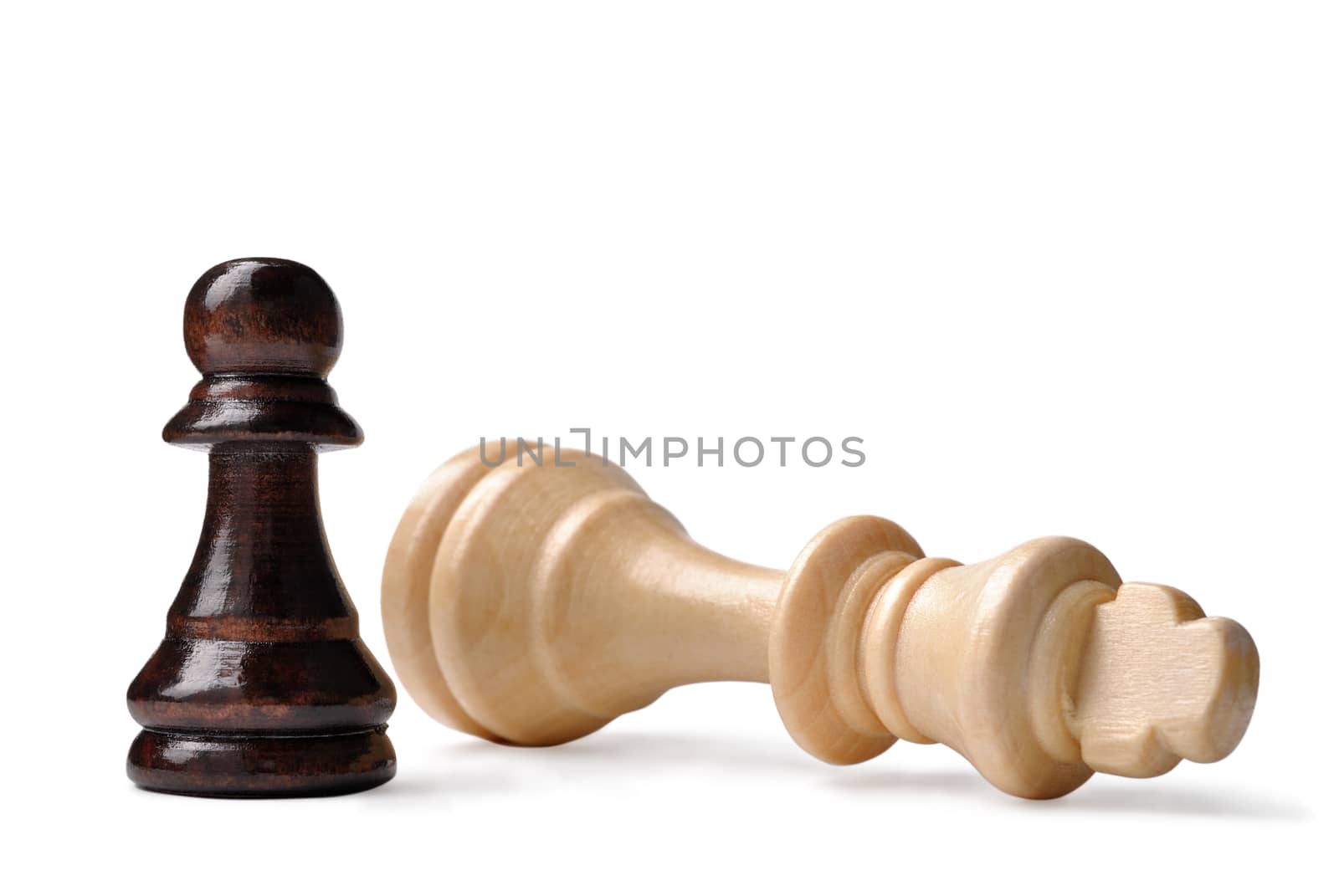 David and Goliath syndrome in chess with a small dark pawn standing triumphant over a fallen light wood king on a white background