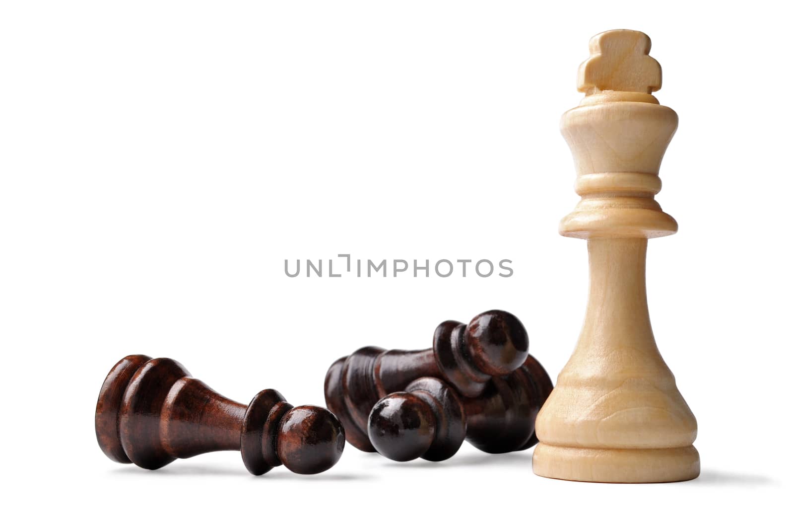 Light coloured wooden King chess piece standing upright surrounded by opposition pawns lying on their side in a game of strategy, on white