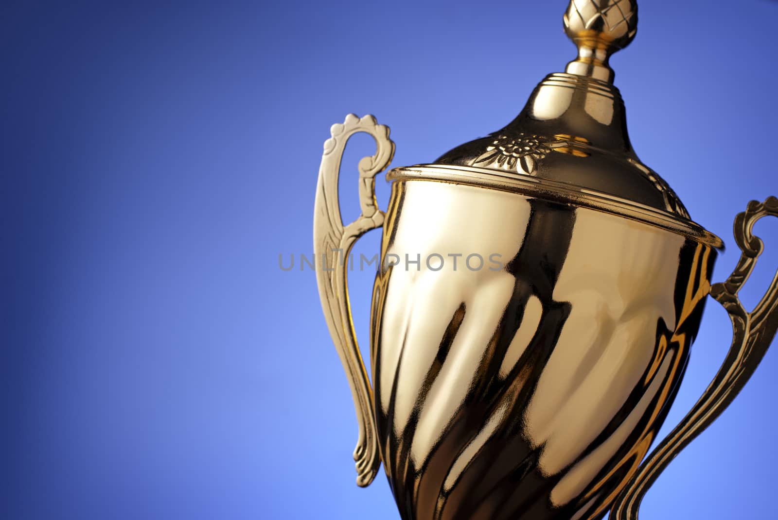 Close up of a silver trophy prize with an ornate lid and handles for the winner of a championship event or competition on blue with copyspace