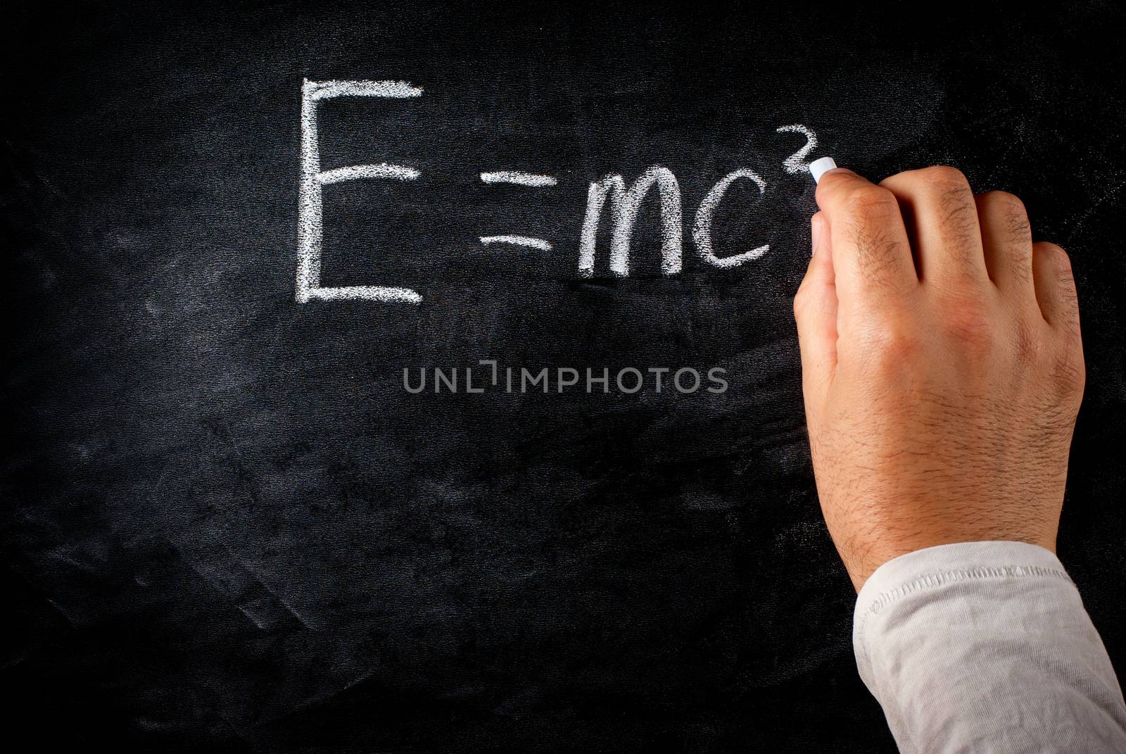 student writing on the chalkboard Einstein's formula e=mc2