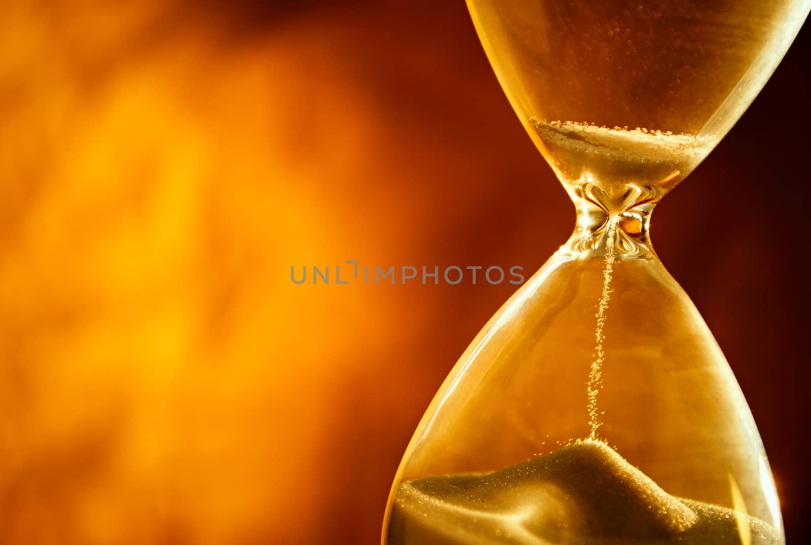 Sand passing through the glass bulbs of an hourglass measuring the passing time as it counts down to a deadline or closure on a yellow background with copyspace