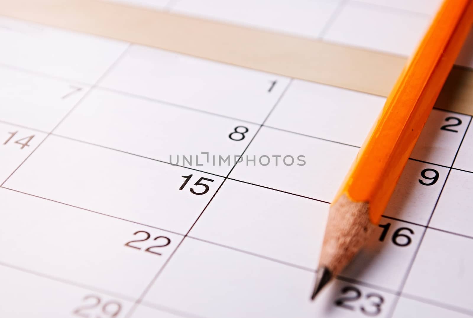 Pencil lying on a calendar with blank squares and dates conceptual of schedules, reminders and organization
