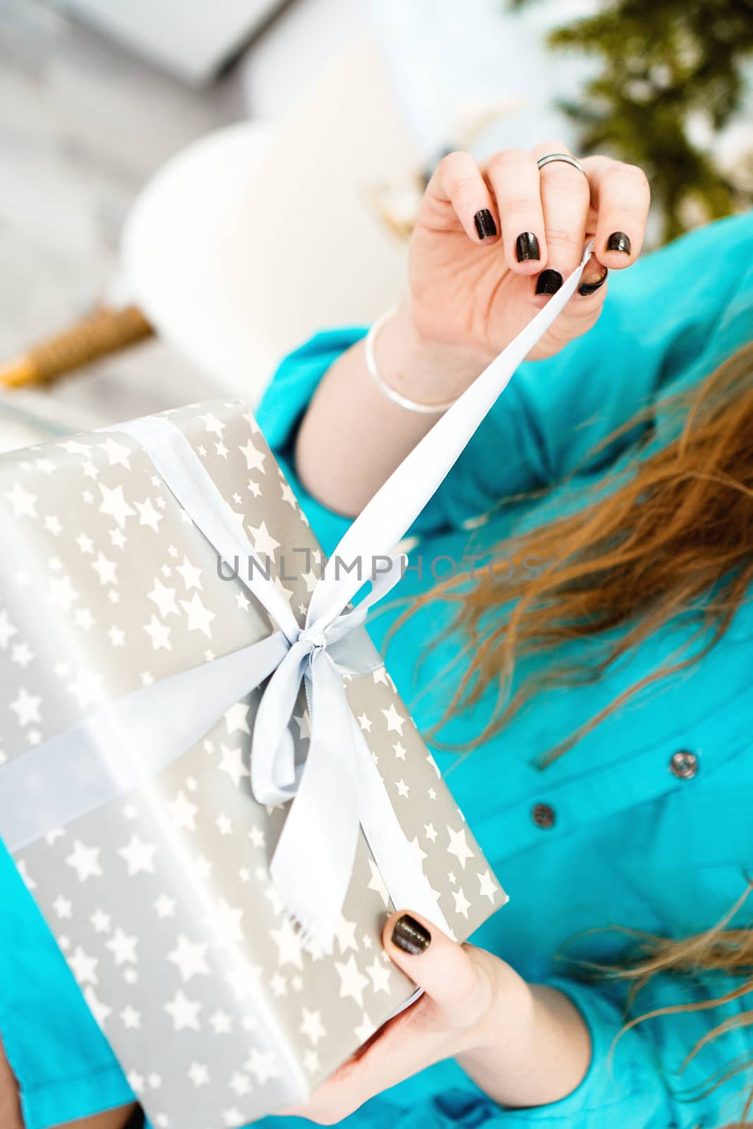 Attractive girl in a blue shirt opens a gift - closeup photo