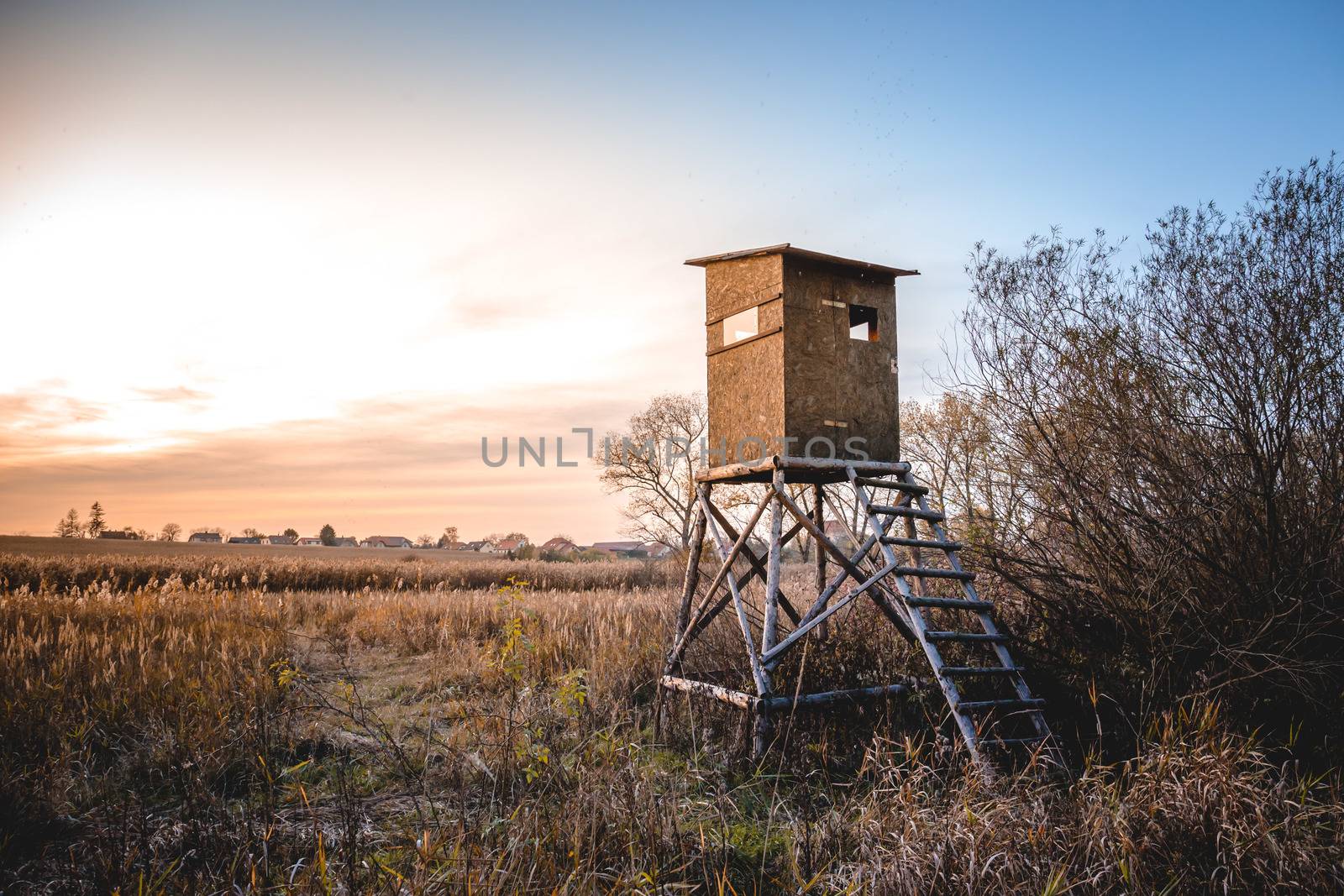 Picture of a hunting tower or a raised hide or blind on a field at dawn. by petrsvoboda91