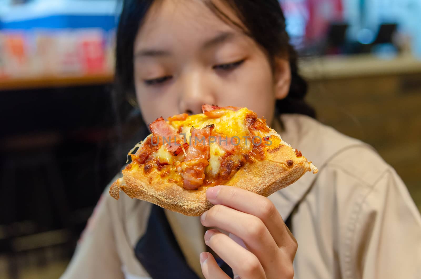 Beautiful Asian girl eating pizza in the restaurant.