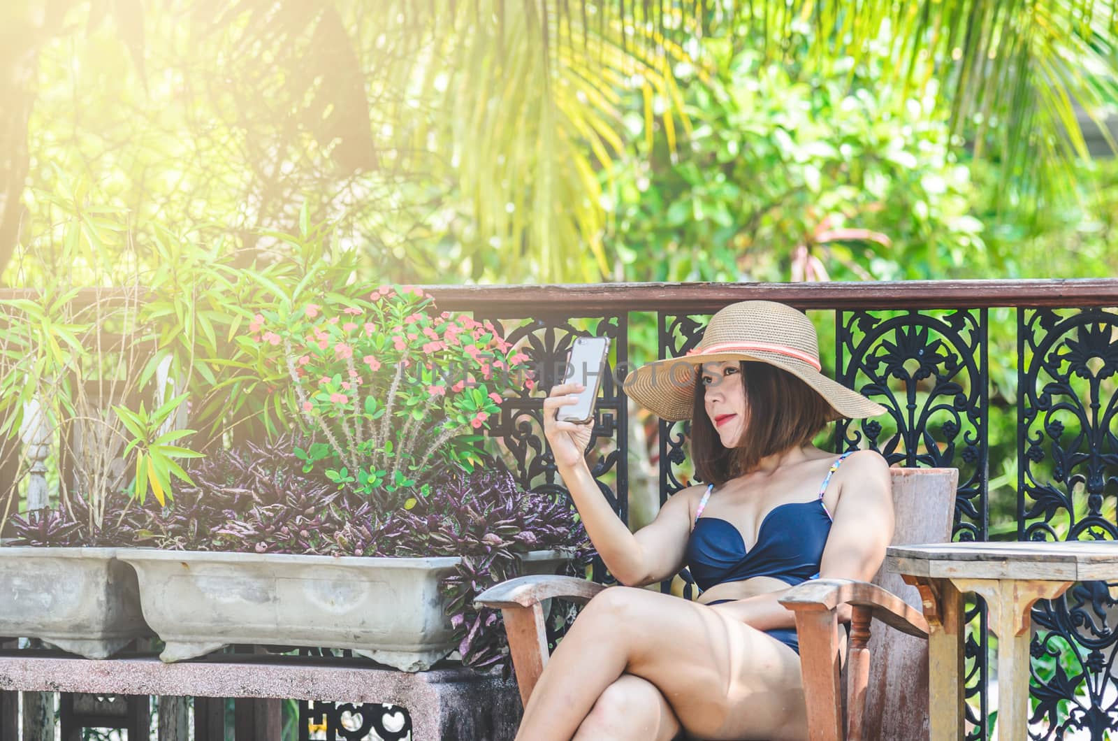Portrait of sexy Asian  woman wearing a  swimsuit play smartphone.