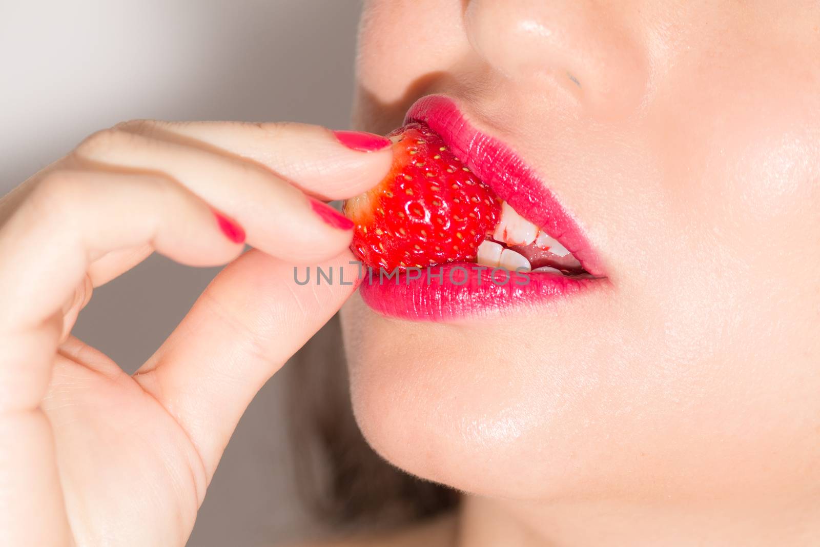 Close up of woman biting a strawberry by leo_de_la_garza
