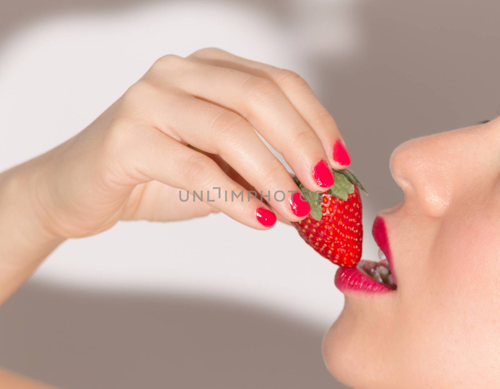 Close up of woman biting a strawberry by leo_de_la_garza