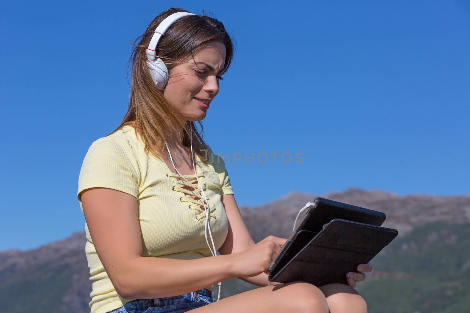 casual woman working with a tablet pc, with headphones, outdoor