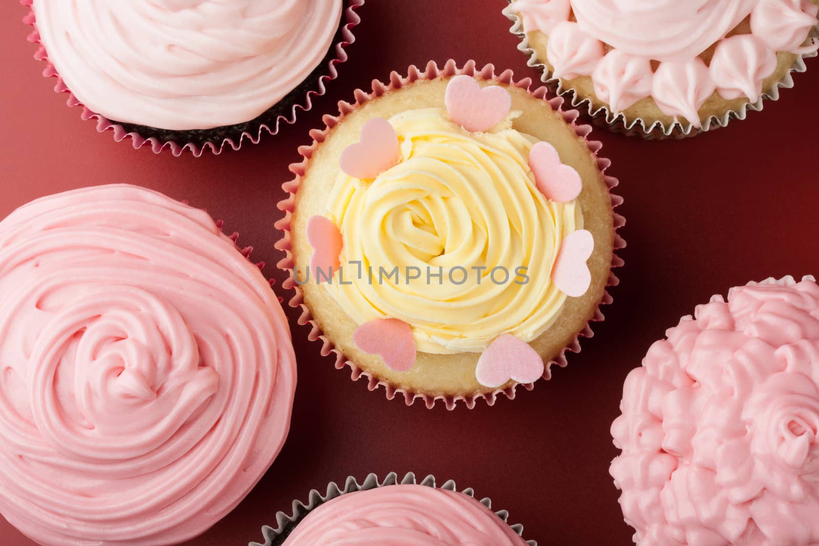 Top view of nice cupcakes with pink icing, red background