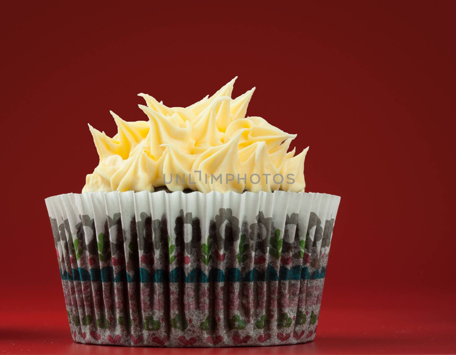 Chocolate cupcake with vanilla spikes icing, red background