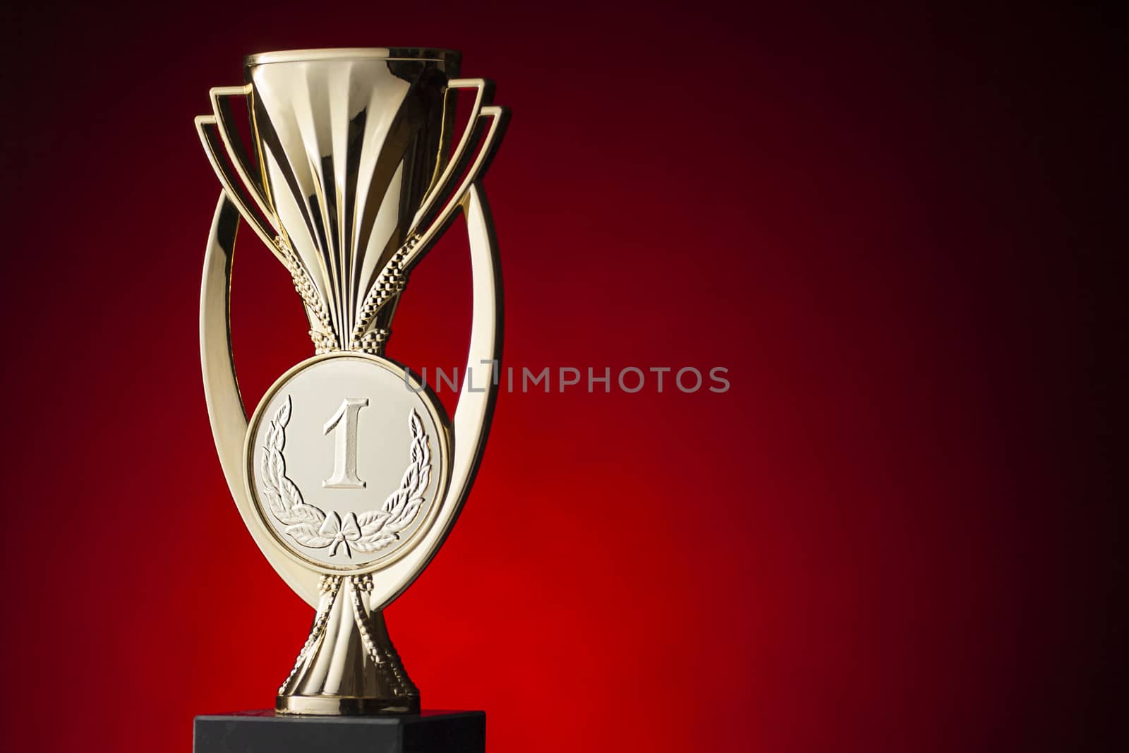 First place winners trophy for a competition or championship with a gold cup and number one over a festive red background with highlight and copy space