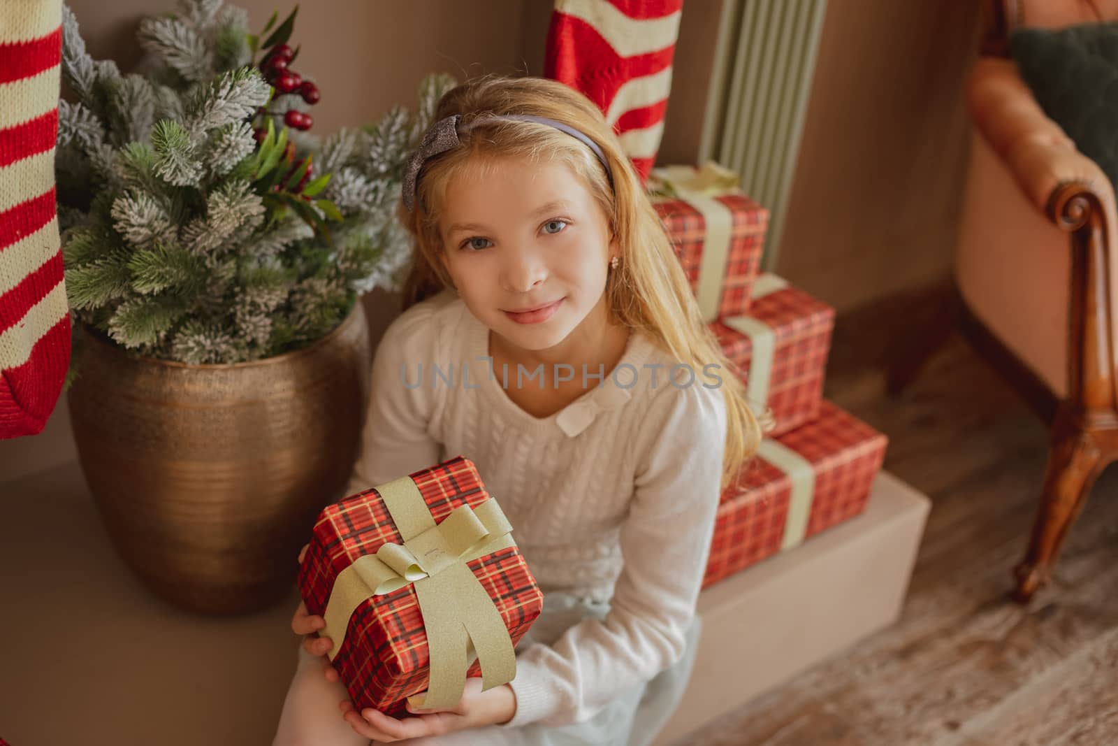 Girl looking on present near Christmas tree by Angel_a