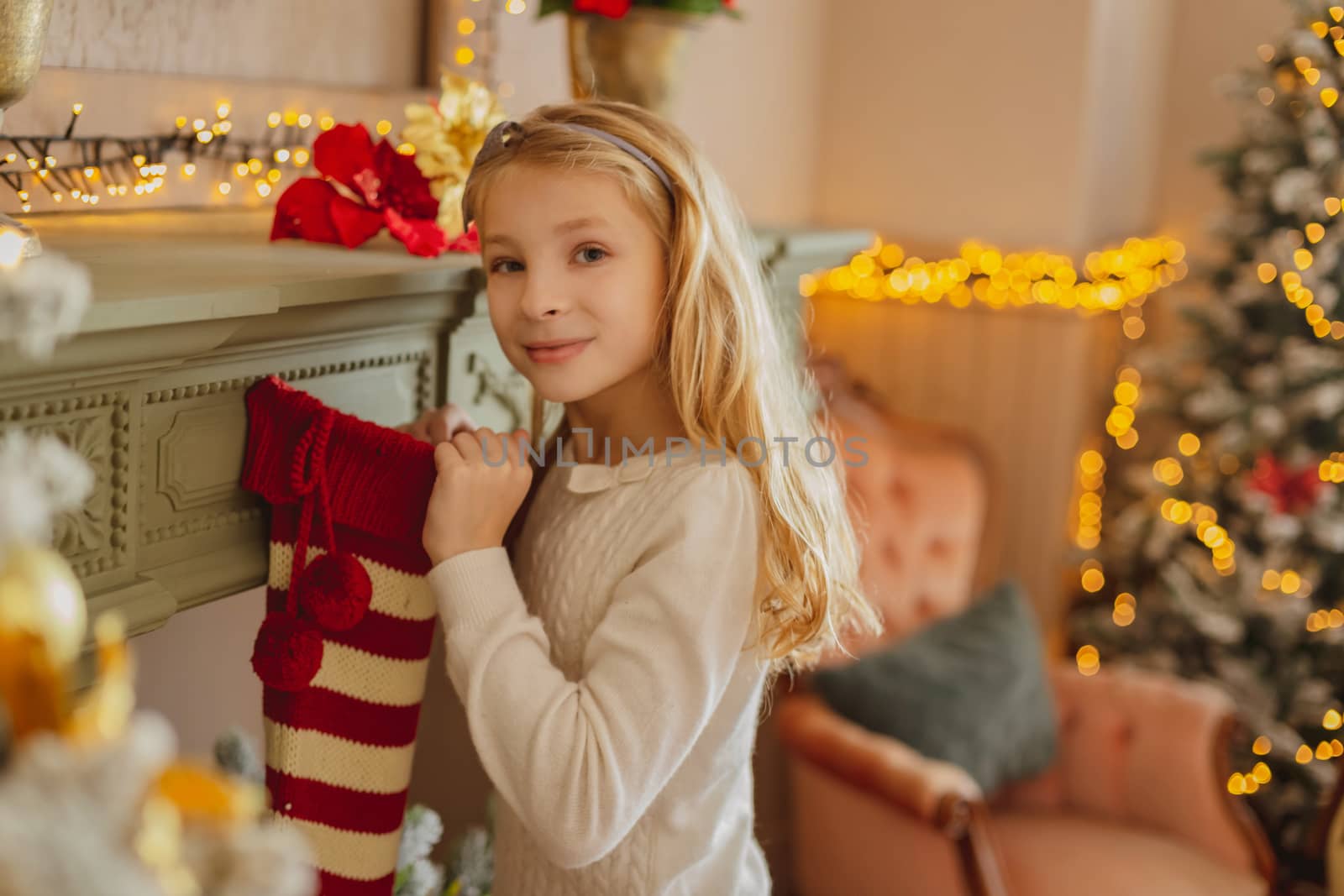 Cute teen girl with present near Christmas tree sitting