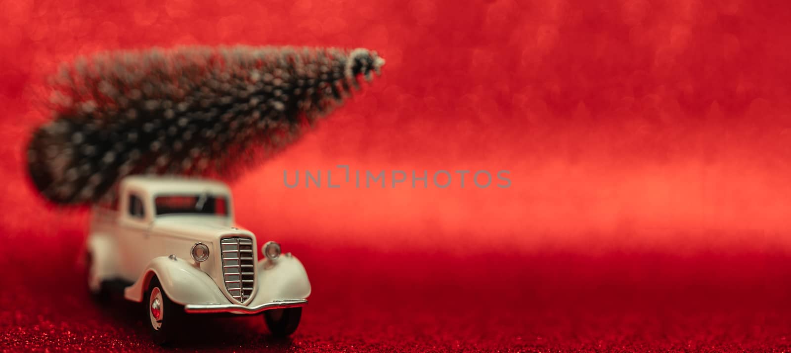 Toy car carries Christmas tree for holiday.