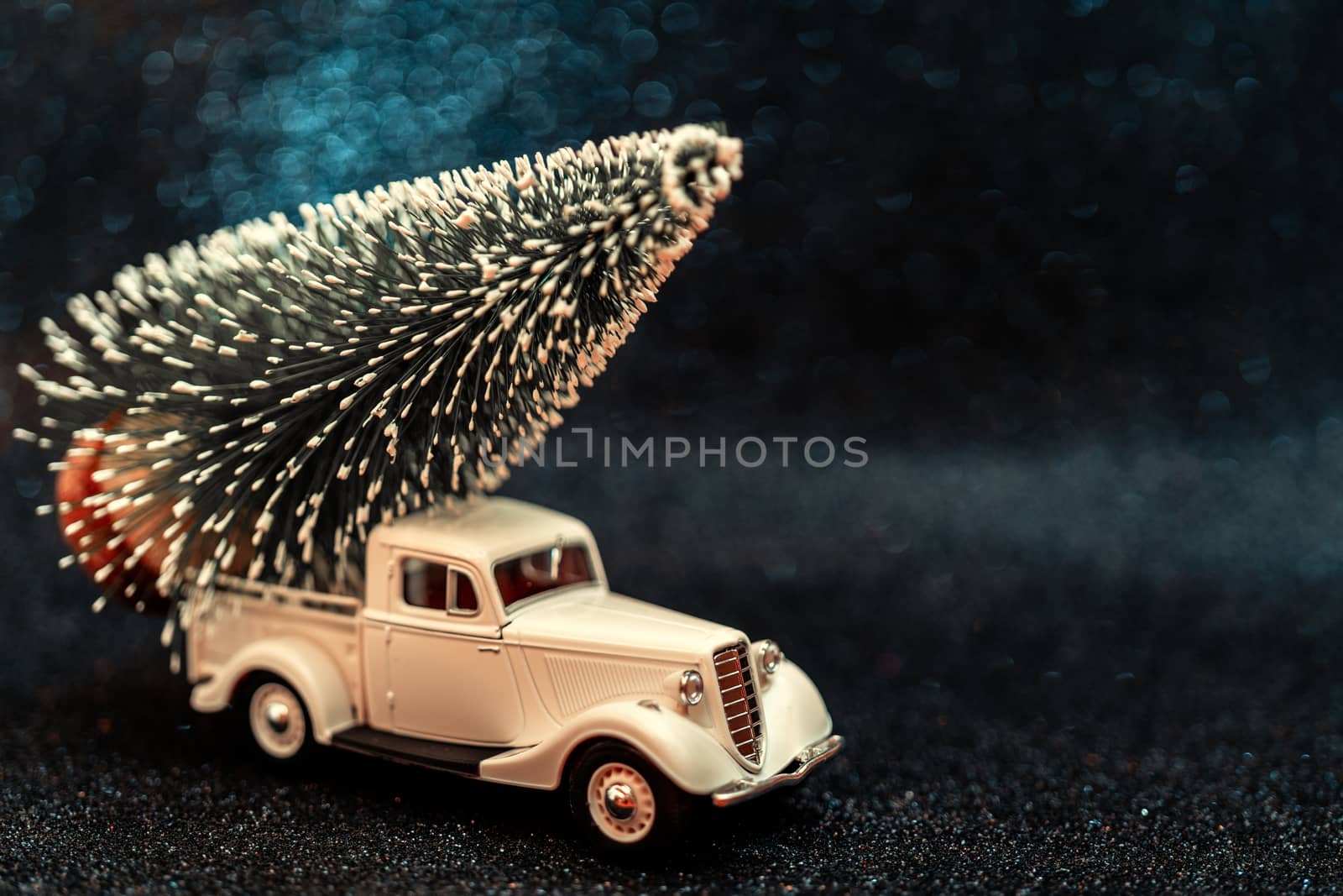 Toy car carries Christmas tree for holiday.