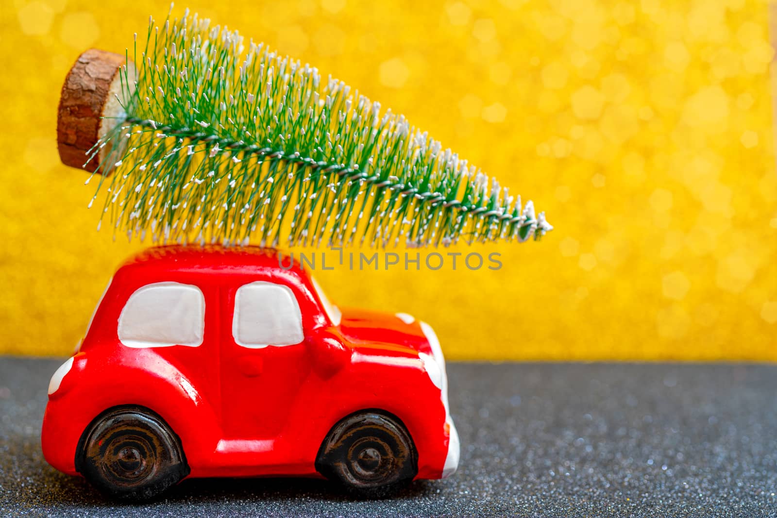 Red toy car carries a Christmas tree for the holiday.
