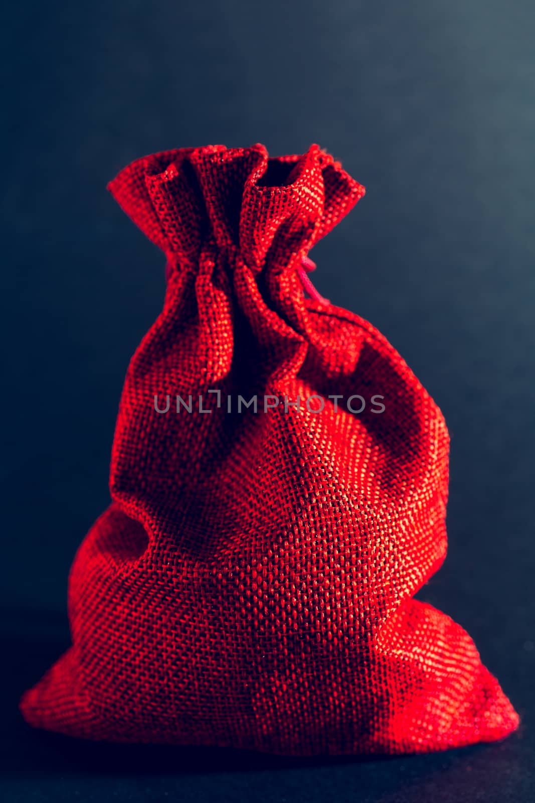 Red bag of Christmas gifts on a black background.