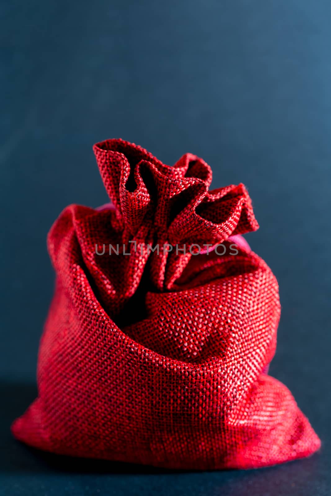 Red bag of Christmas gifts on a black background.