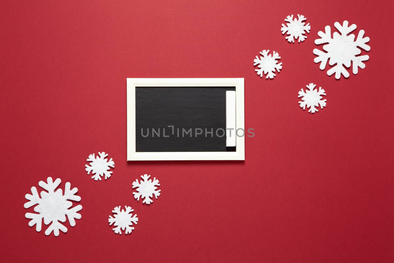 Christmas composition, small chalk board, frame of snowflakes with copy space on dark red background. Blank for postcard layout. Festive, New Year concept. Horizontal, flat lay. Minimal style.
