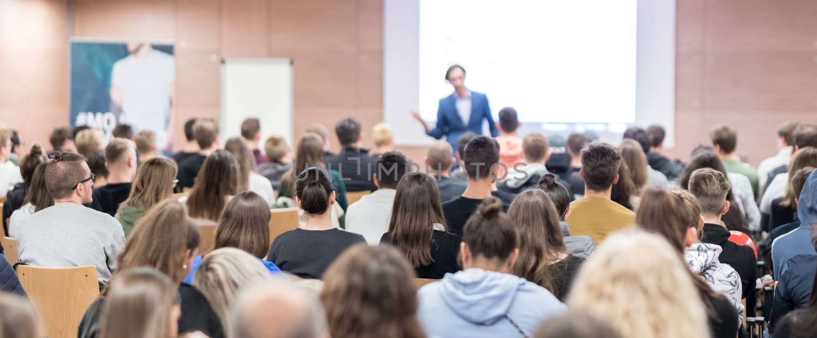 Speaker giving a talk in conference hall at business event. Audience at the conference hall. Business and Entrepreneurship concept. Focus on unrecognizable people in audience.