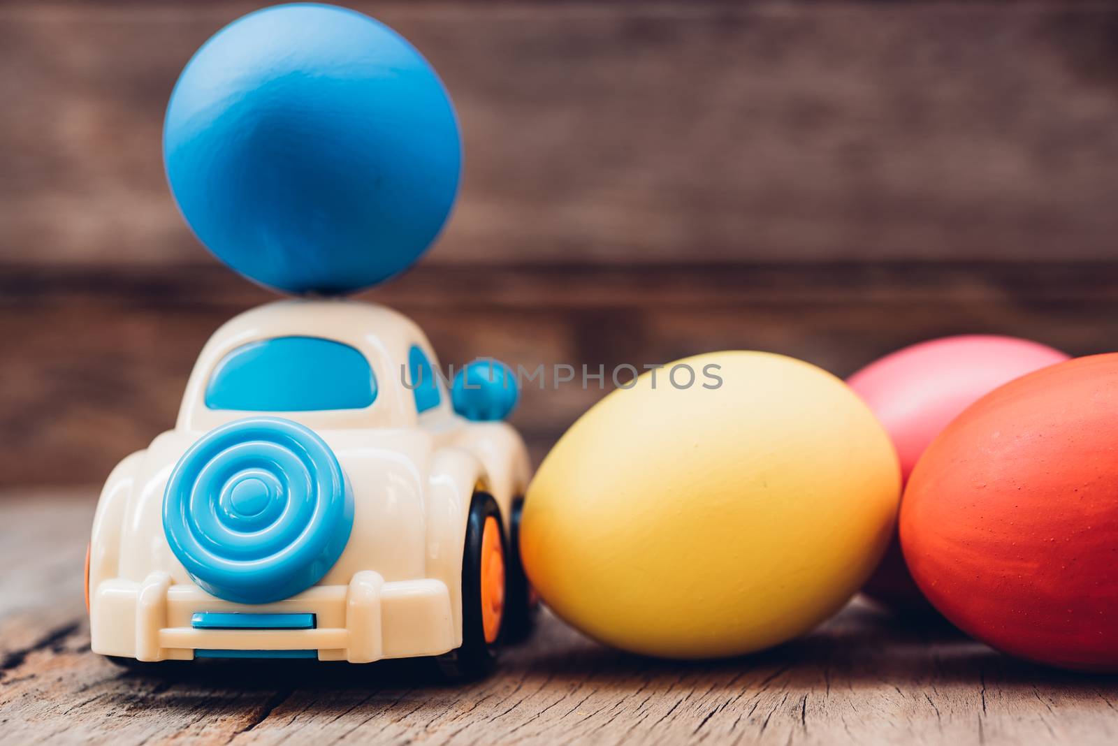 Easter egg and toy car on wooden background, happy easter day concept